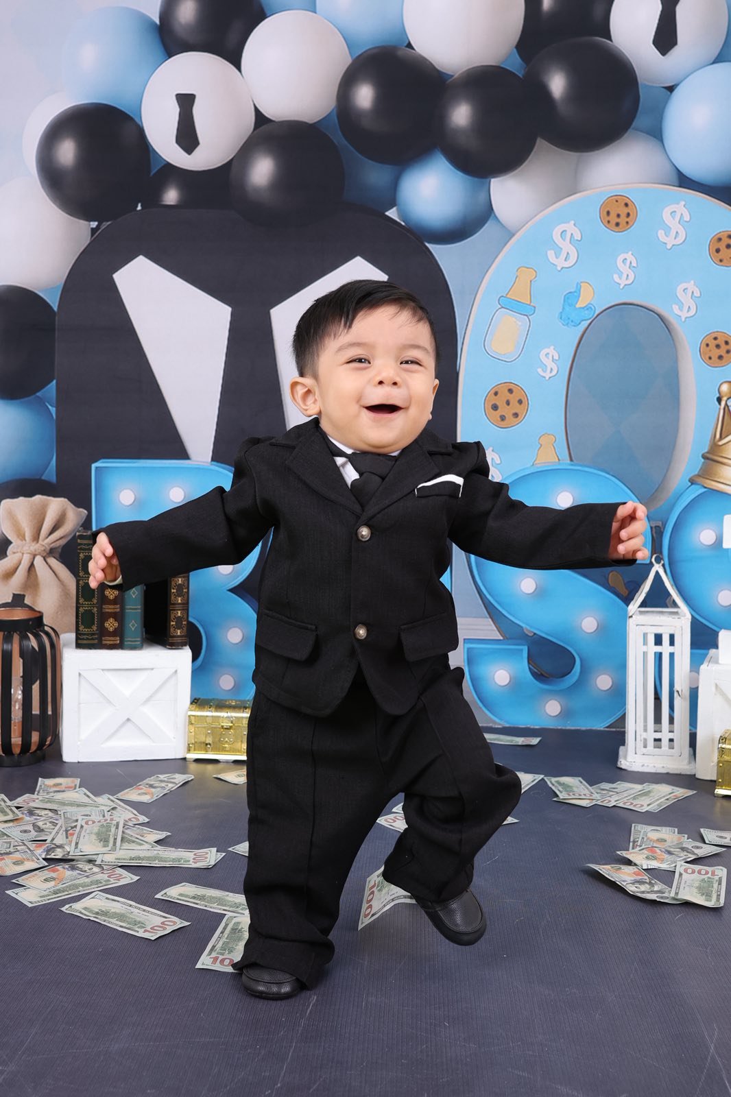 Archer dressed as Boss Baby in a black suit smiling happily